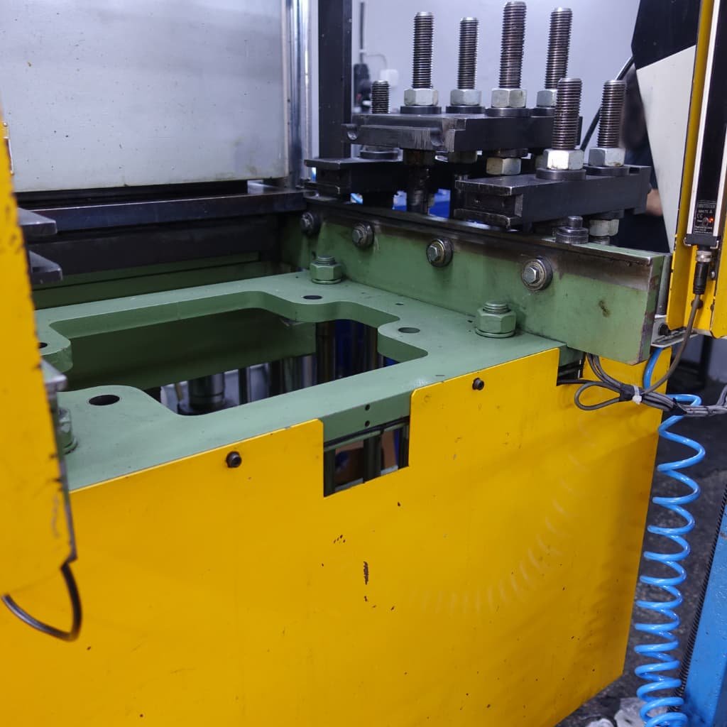 Máquina hidráulica industrial con protección perimetral amarilla y sistema de sujeción, certificada con el marcado CE según la Directiva de Máquinas 2006/42/CE.