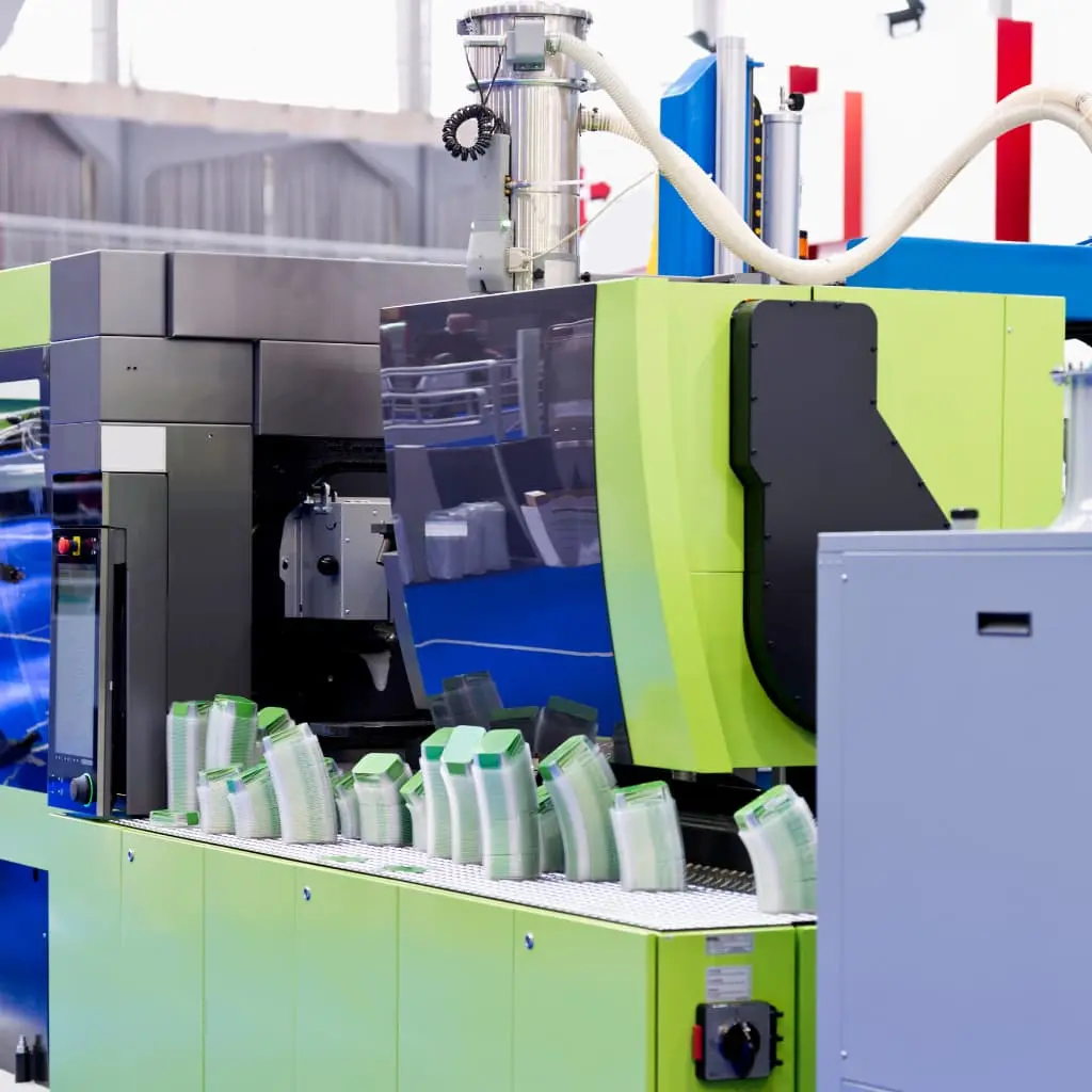 Máquina de inyección de plasticos en funcionamiento dentro de una planta de automoción