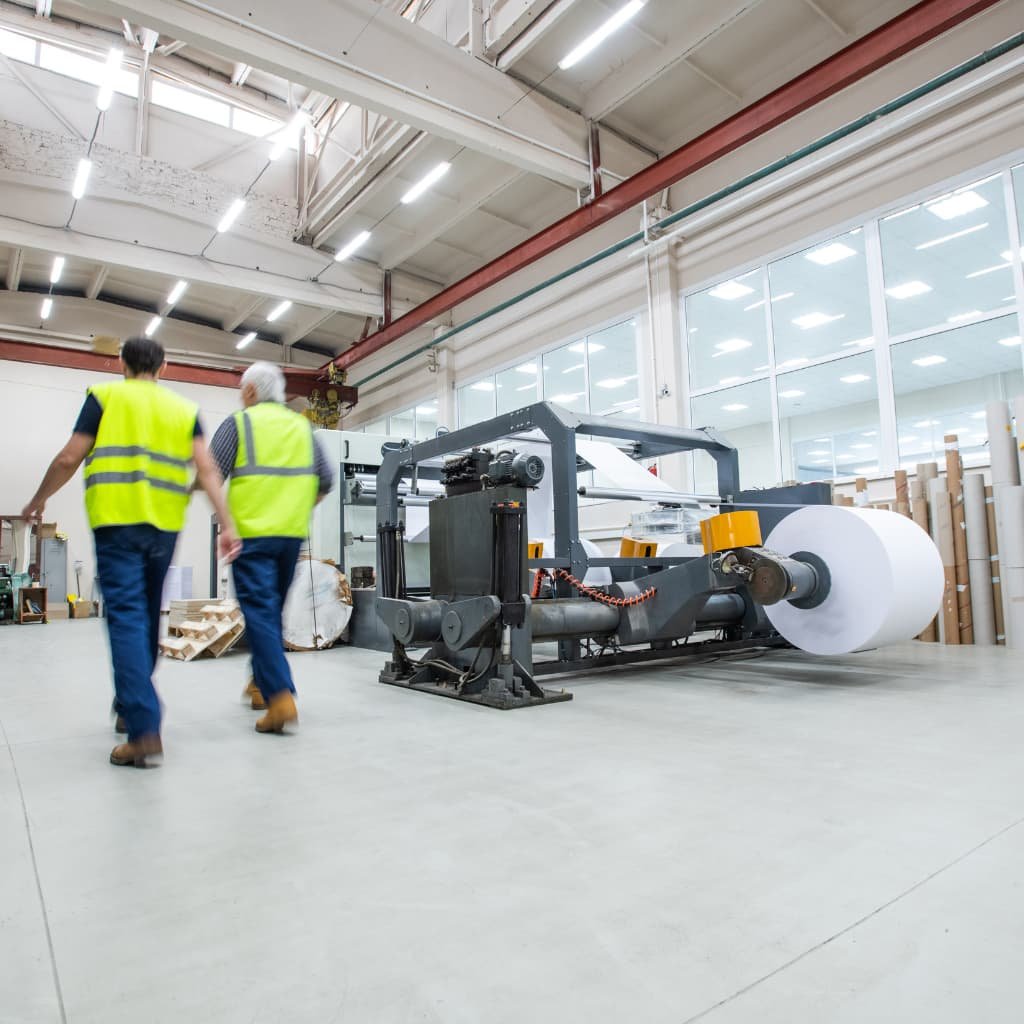 Trabajadores en planta industrial durante la inspección de seguridad en máquina de producción.